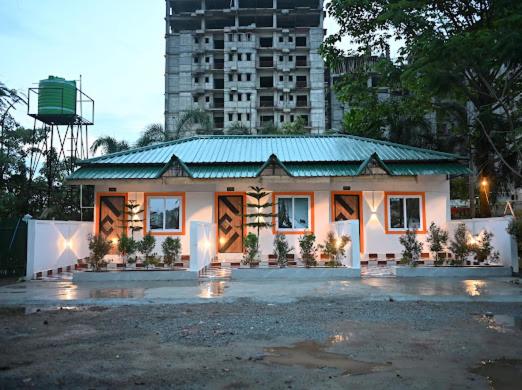 a house with a green roof in front of a building at SHANKARDHABA&resort in Guwahati