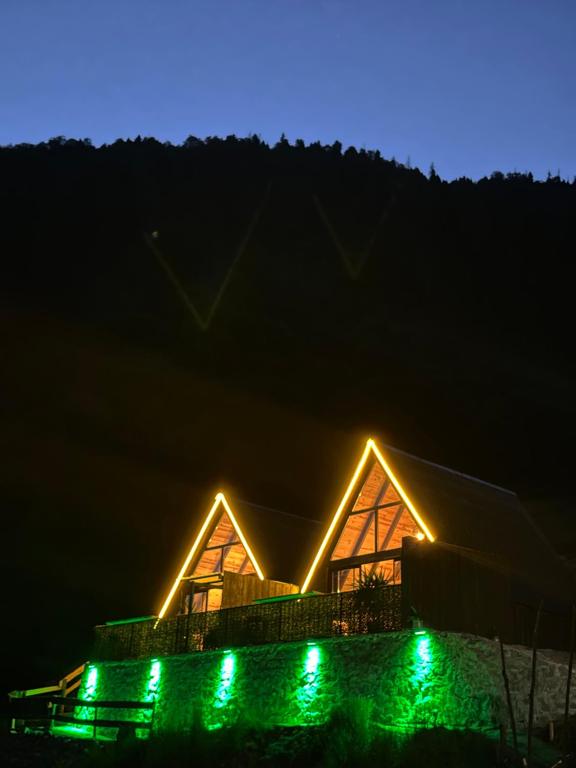 a house lit up at night with green lights at Peak ayder bungalow in Ayder Yaylasi