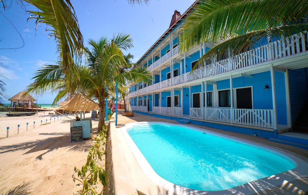 a blue building with a swimming pool next to a beach at El Faro Beach Front by ÓOL Hotels in Holbox Island