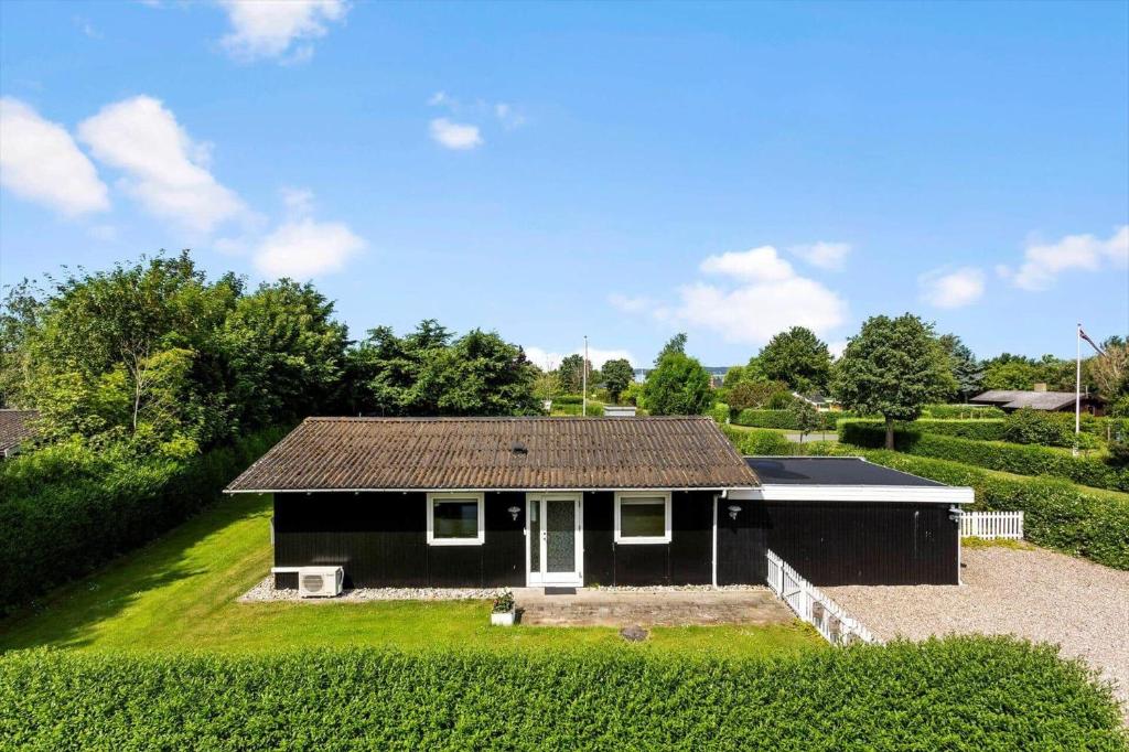 a small black house with a roof on a yard at LL275-svendborg-Stenklovervej-2 in Svendborg