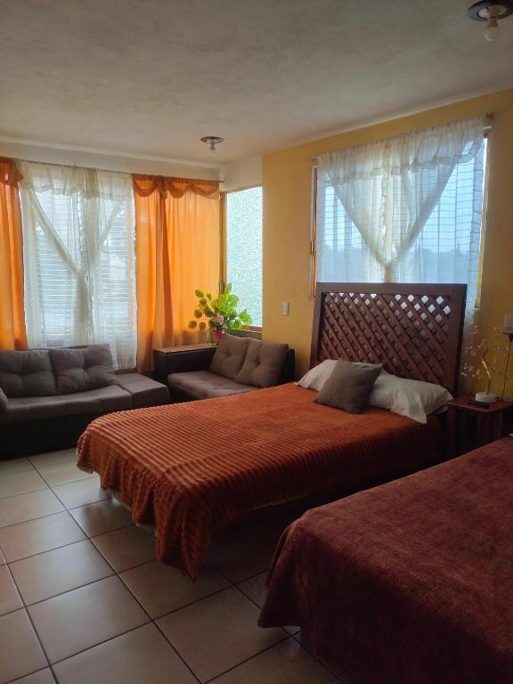 a bedroom with two beds and a couch and windows at DEPA3 4 personas SanFco in Zacatlán