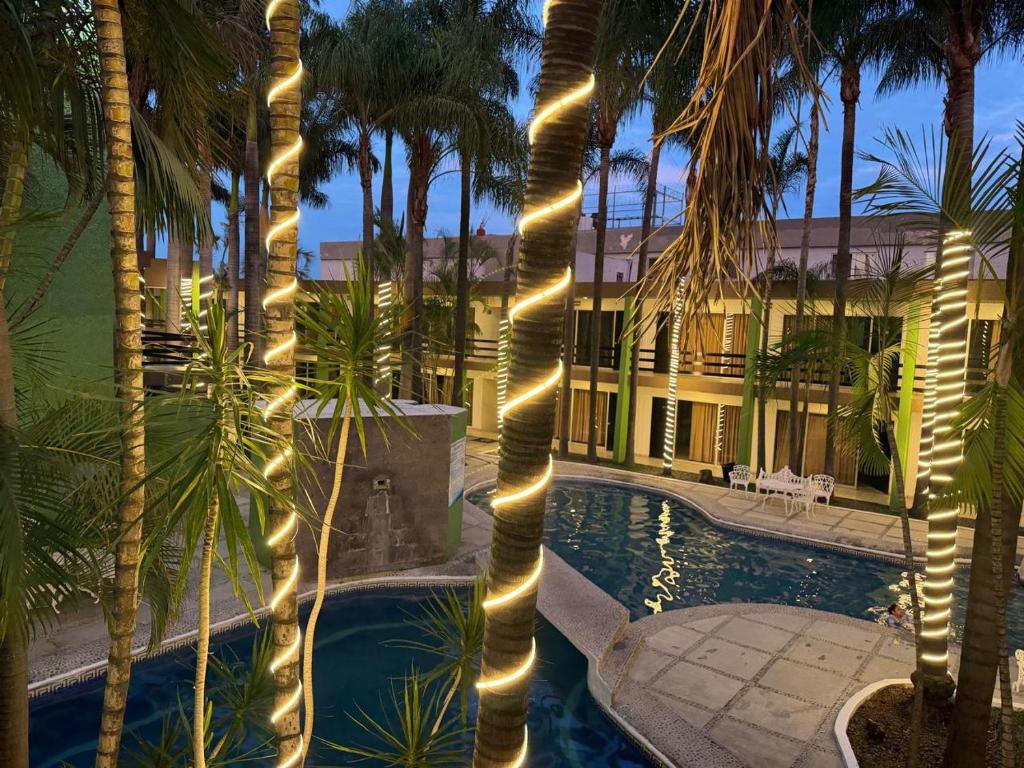 a resort with a swimming pool with palm trees and lights at Hotel Solé Plaza Guadalajara in Guadalajara