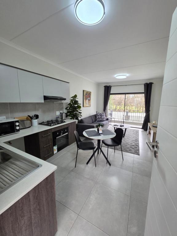a kitchen and living room with a table and chairs at 77 on Par in Boksburg