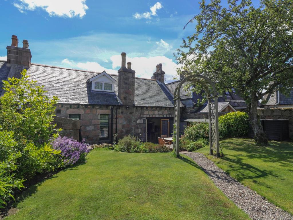 an old stone house with a garden in front of it at St Kilda in Ballater