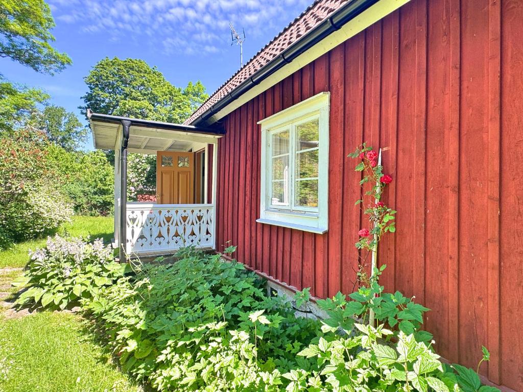 ein rotes Haus mit einer weißen Veranda und einem Fenster in der Unterkunft Hus Mida in Högsby