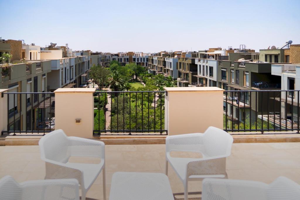 a row of white chairs on a balcony with buildings at 33A4. Rooftop Studio w Terrace Green Views in Sheikh Zayed