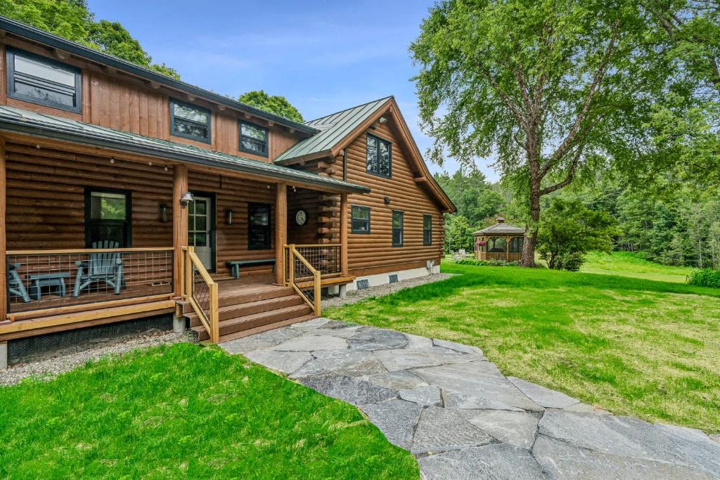 a log home with a porch and a yard at Log Cabin Fireplace Upper Valley - Wooded Chalet in Hartland