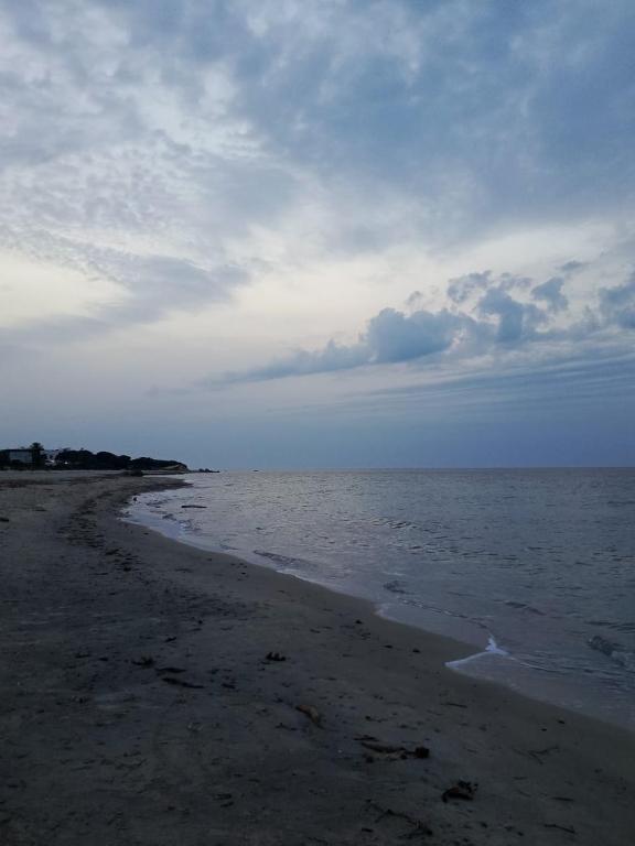 a beach with a cloudy sky and the ocean at maison entre forêt et mer in Raʼs al Jabal
