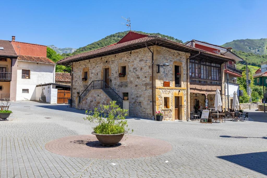 a large stone building with a pot in the middle of a street at Apartamentos San Roque in Arenas de Cabrales