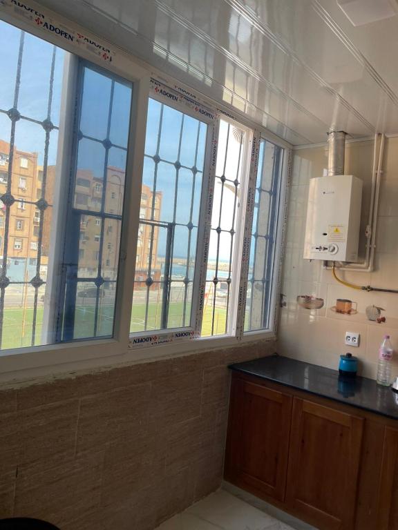 a kitchen with three windows and a counter in a room at Front de mer salamndre in Mostaganem