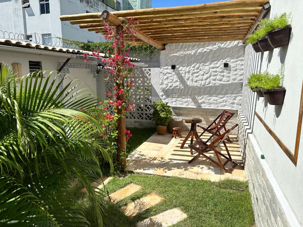 a garden with a pergola and a table and flowers at Pousada Flor do Sol in Fortaleza
