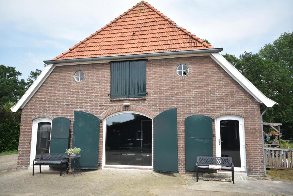 a red brick building with two benches in front at De Vechthoeve in Dalfsen