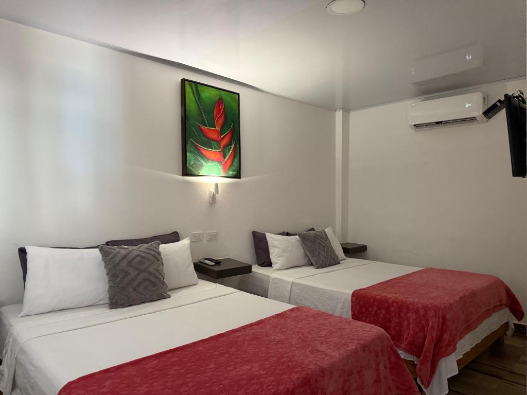 a room with two beds and a painting on the wall at Hotel Sunset Beach in Cartagena de Indias