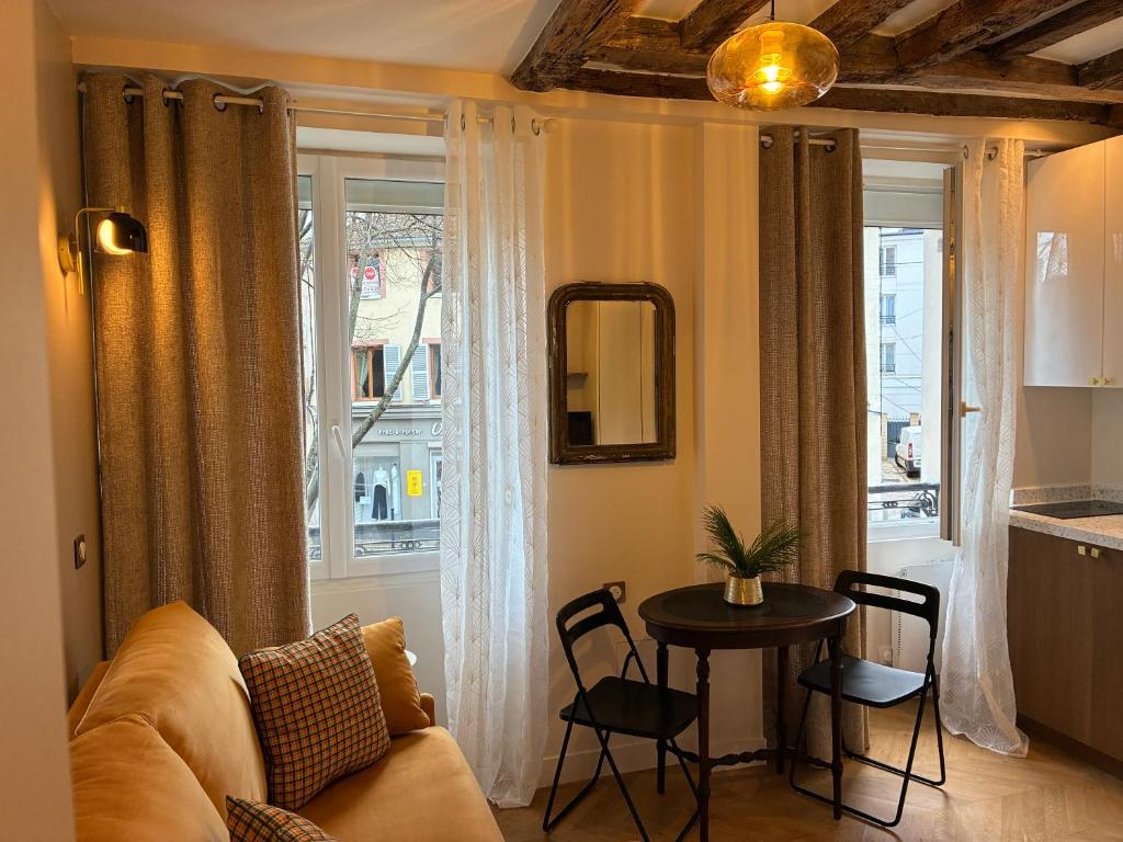 a living room with a couch and a table and a window at Studio cosy avec parking près de Paris Expo Porte de Versailles in Vanves