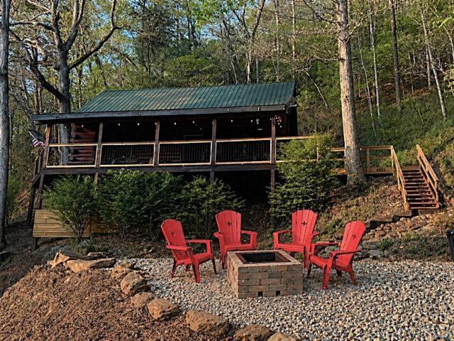 a group of red chairs in front of a cabin at UnBearably Cozy - pool table, fire pit, central location in Bryson City