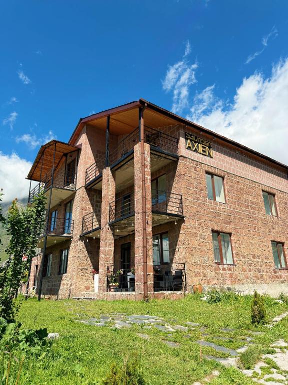 ein großes Backsteingebäude mit einem Schild darauf in der Unterkunft Hotel Axien Kazbegi in Kazbegi
