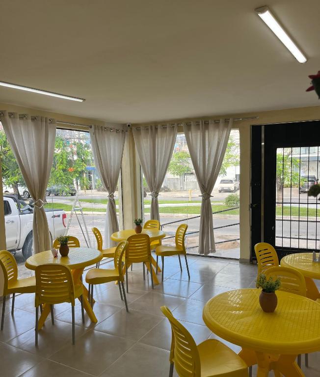 a restaurant with yellow tables and chairs and windows at Pousada Mar de Pajuçara in Maceió