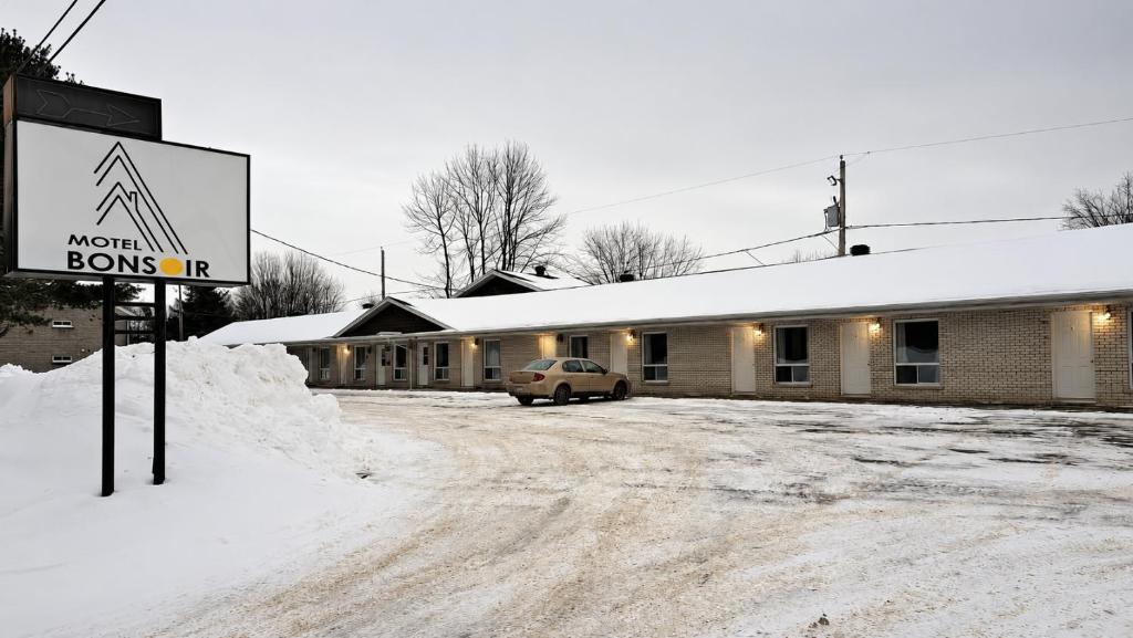 a sign in the snow in front of a building at Motel Bonsoir in Joliette