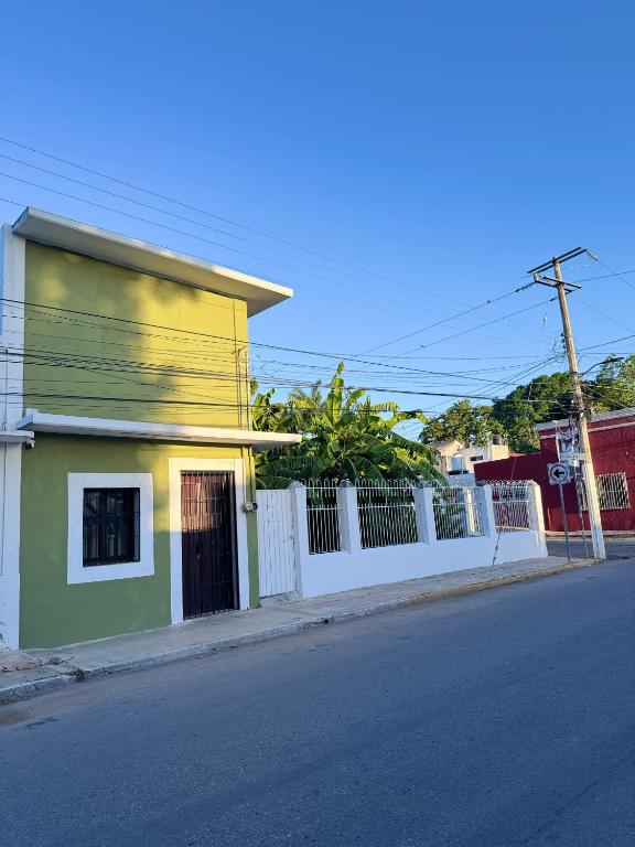 a yellow and green building next to a white fence at Casa verde El Platanar con Jardín Tropical Calkiní in Calkiní
