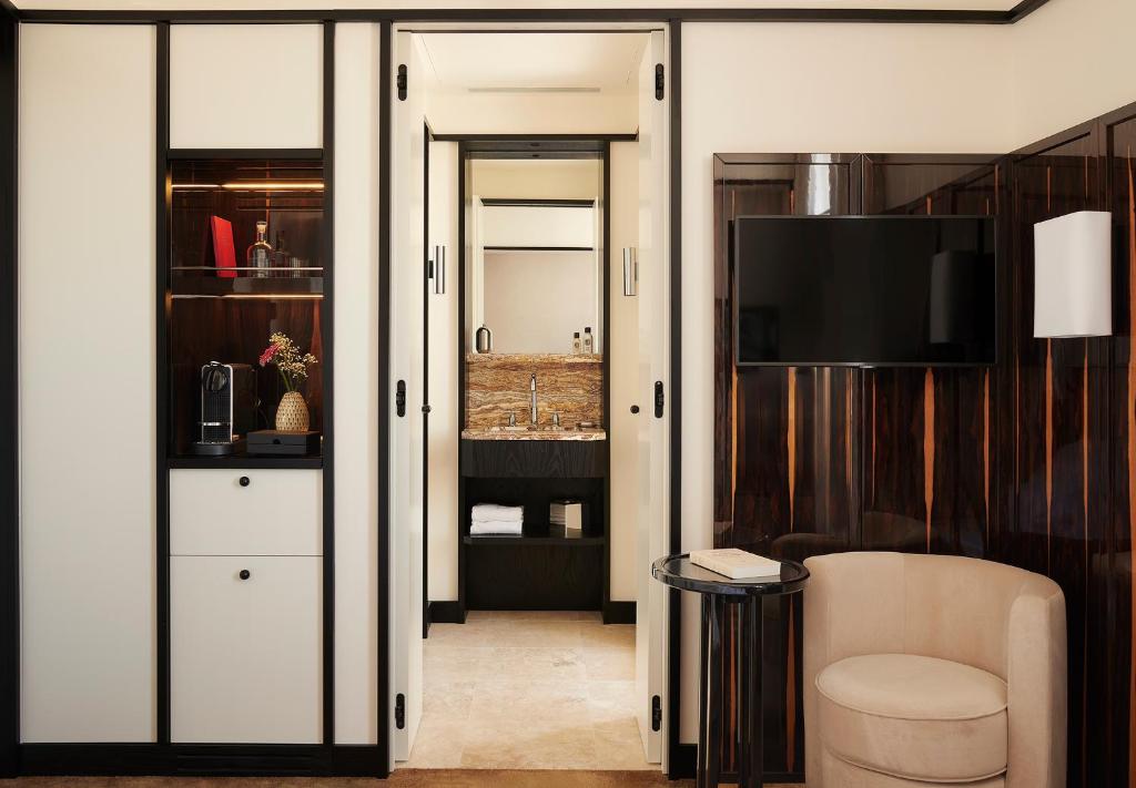 a living room with a television and a couch and a chair at Hôtel Atlas in Paris