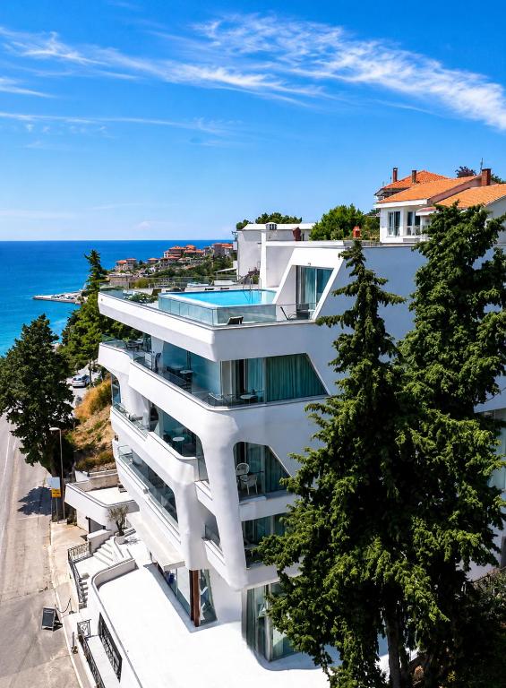 a white building with trees in front of the ocean at ARABESQUE Apartments & Suite in Ulcinj