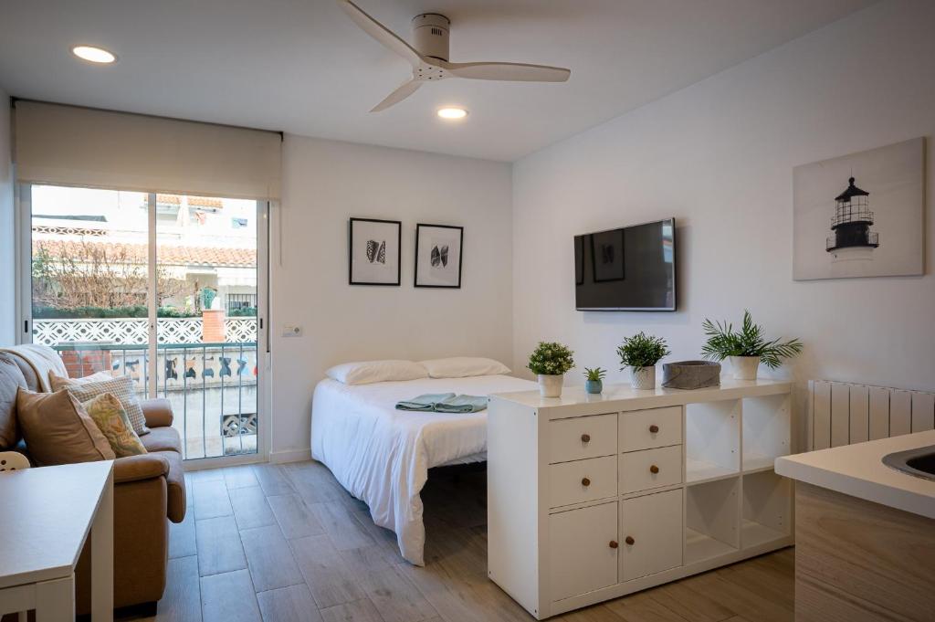 a white bedroom with a bed and a tv at Acogedor studio a 10min de la playa in Torredembarra
