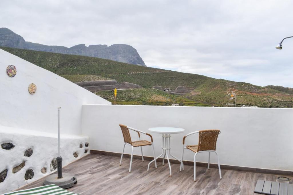 a balcony with a table and chairs and a mountain at Casa El Nido, Agaete in Agaete