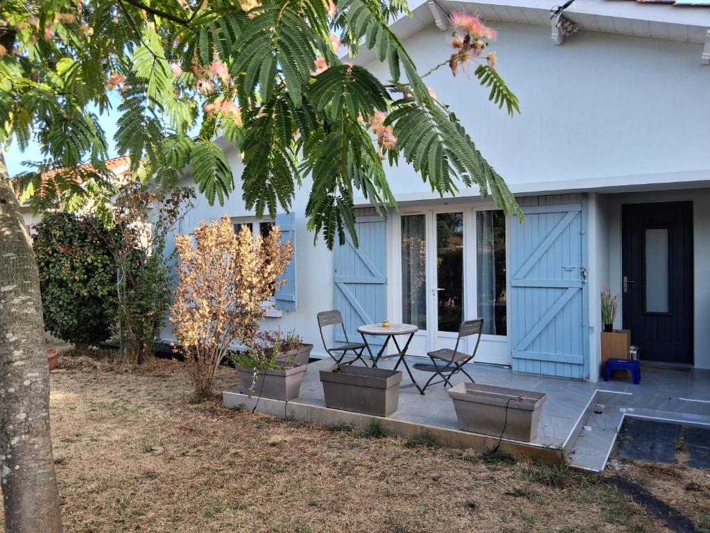 a patio with a table and chairs in front of a house at Maison proche bassin et océan in Arès