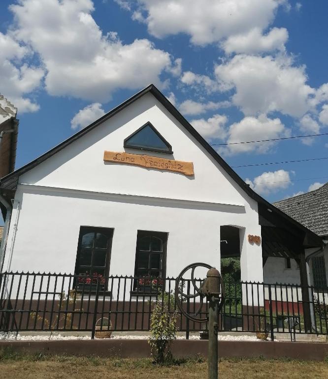 a white building with a black fence at Luna Vendégház in Ipolyvece