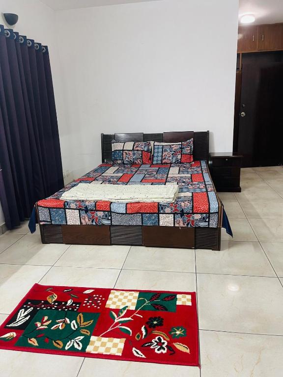 a bedroom with a bed and two rugs on the floor at Elegant Residence Guest House in Dhaka