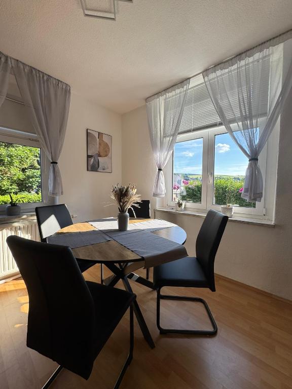 a dining room with a table and chairs and windows at ErzNest in Thum