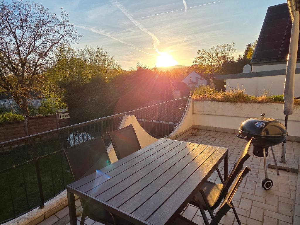 a wooden table on a balcony with the sunset in the background at Chalet Annemie in Mendig