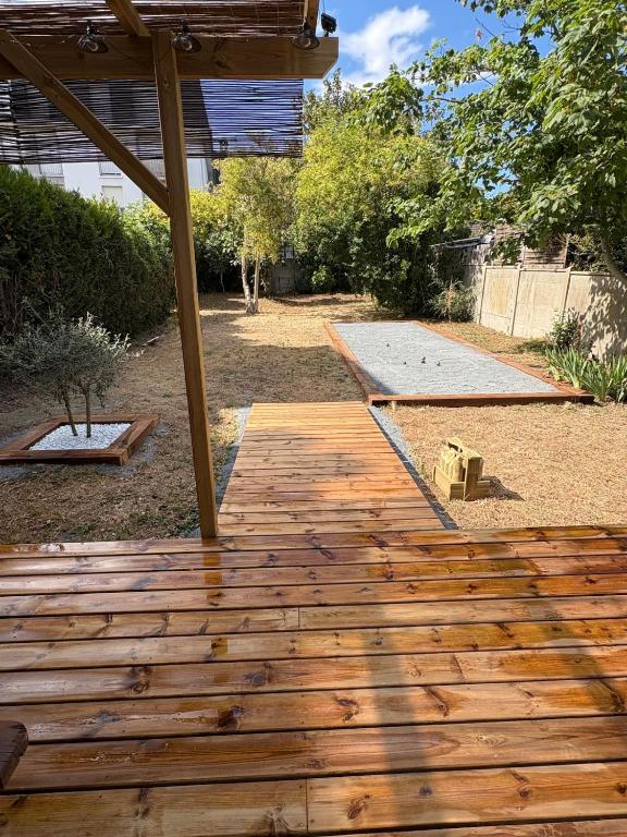 a wooden walkway in a yard with a canopy at CAEN ça repose ! in Caen