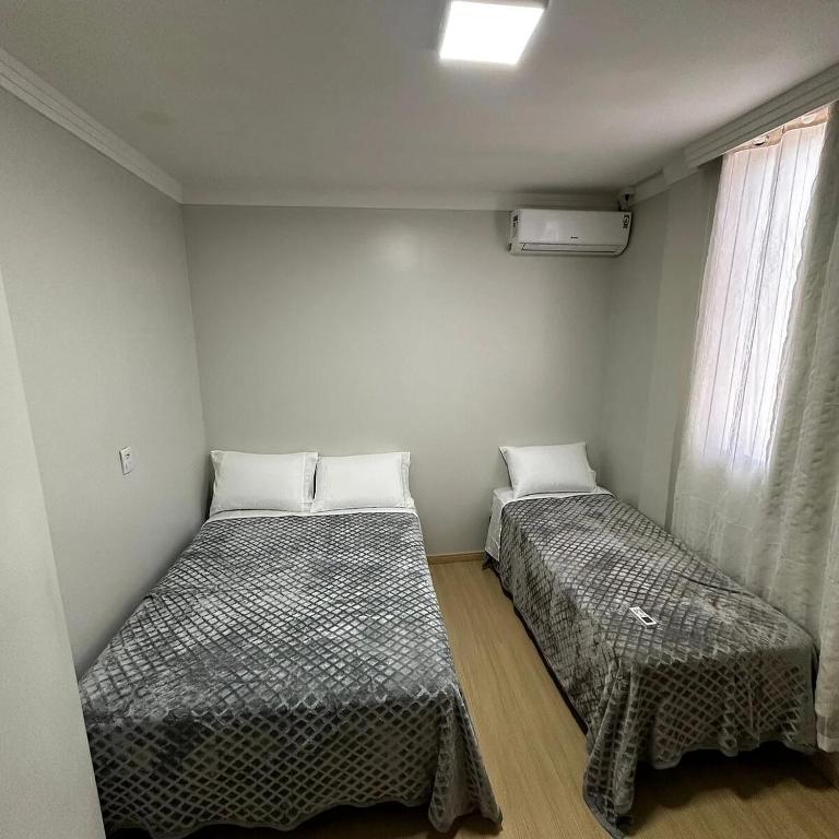 two beds in a small room with a window at Loft Lux SM Chapecó com excelente localização! in Chapecó