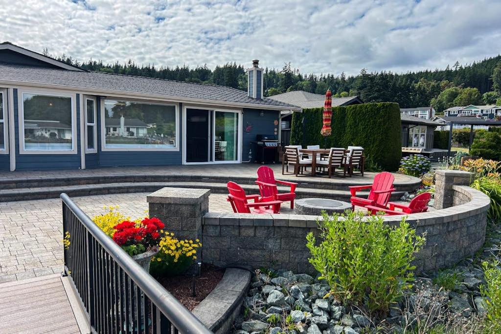 a patio with red chairs and tables in front of a house at Whidbey Mariners’ Retreat in Oak Harbor