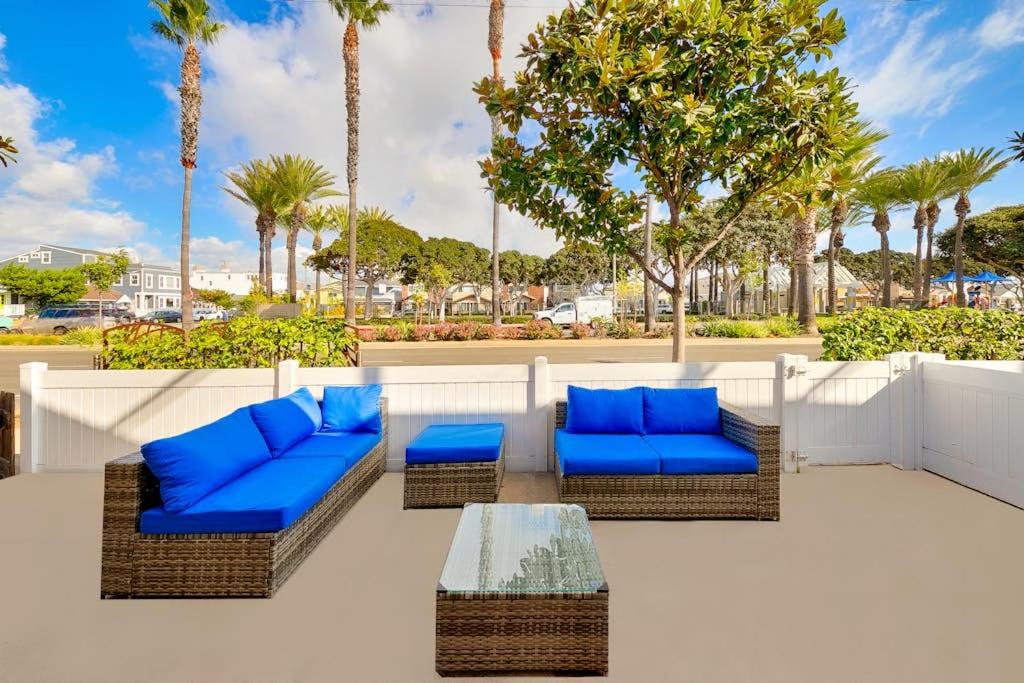a patio with blue chairs and a table and palm trees at Balboa Duplex in Newport Beach