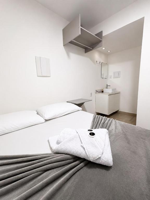 a white bedroom with a bed with a towel on it at Manaira Suite 01 in João Pessoa
