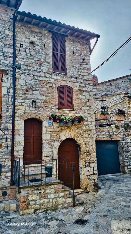 a stone building with two doors and flowers on it at Casa Picicio in Assisi