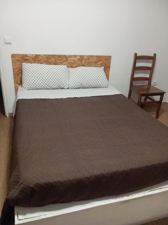 a bed in a room with a chair at Refúgio da Estrela Covilhã in Covilhã