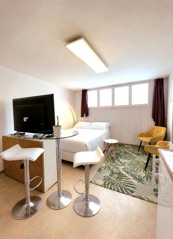a hotel room with a bed and a tv and chairs at Petit Biscuit - Wi-Fi - Kitchen - AC - Parking in Lido di Camaiore