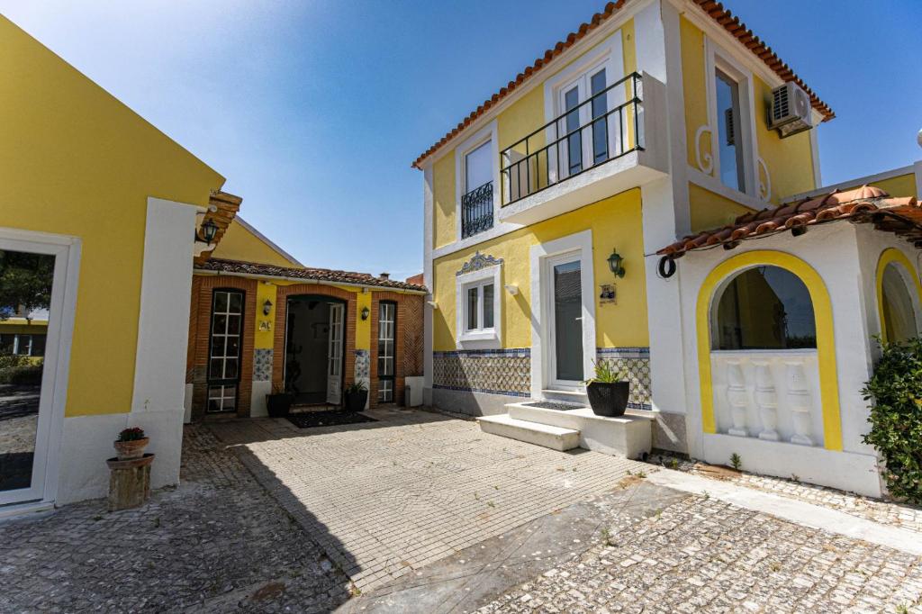 a yellow and white house with a courtyard at Quinta dos Canais in Setúbal