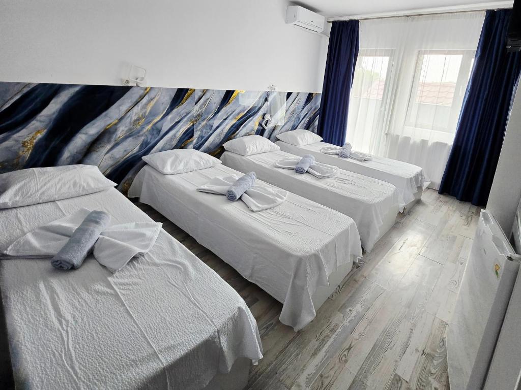 ein Zimmer mit drei Betten mit blauen Schleifen in der Unterkunft Ridos in Constanţa