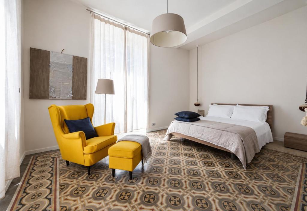 a bedroom with a bed and a yellow chair at Casa Vacanza Baragiola4 - Hotel San Giuseppe Group in Cernobbio