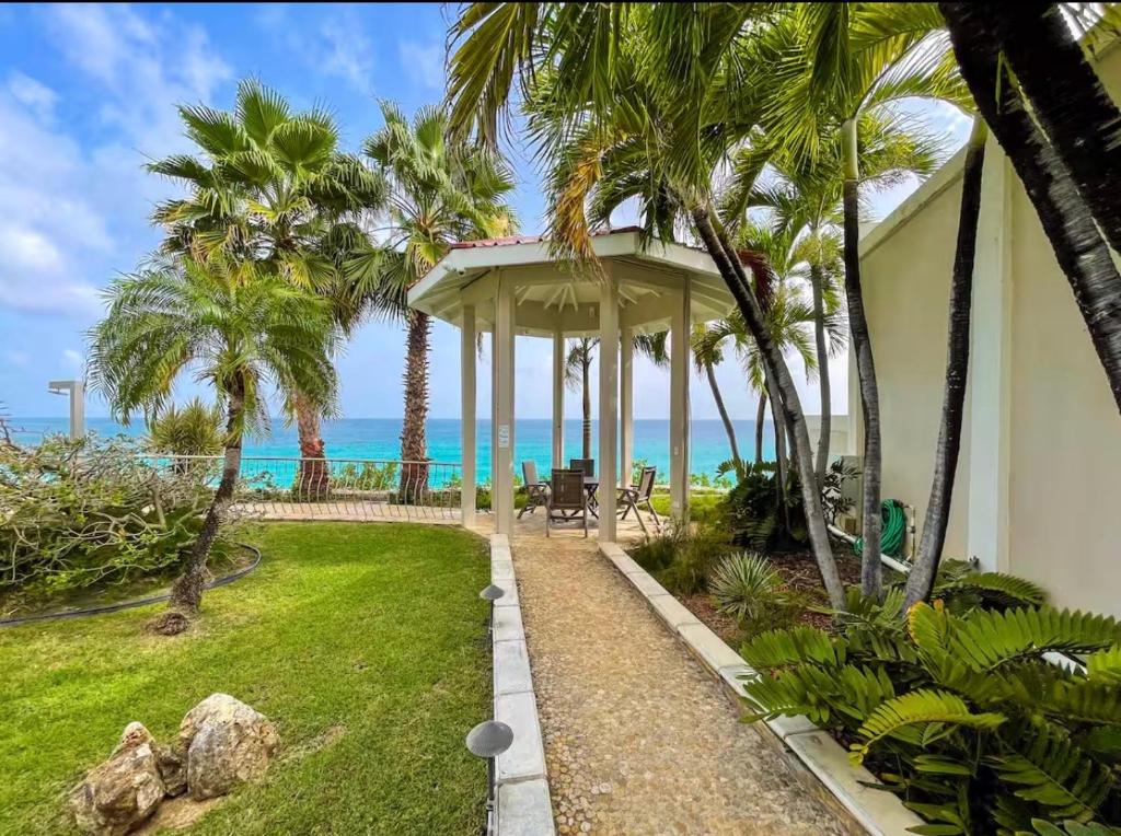 a house with a garden with palm trees and the ocean at Ocean View Serenity in Cupecoy