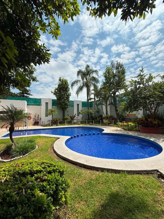 a swimming pool in a yard with trees and a building at Áurea Hotel and Suites in Guadalajara