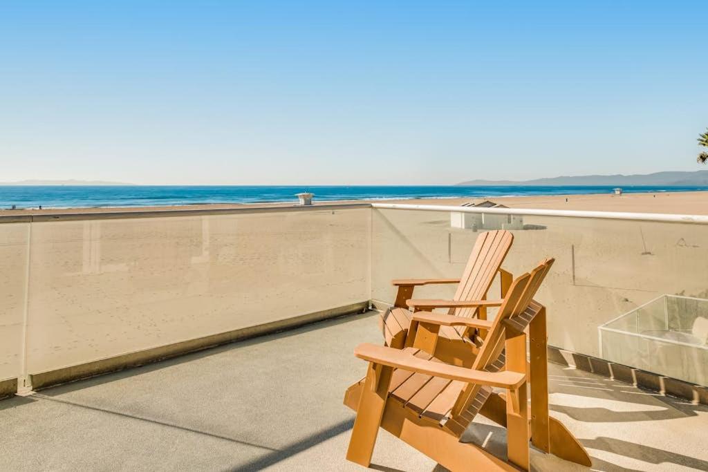 two wooden chairs sitting on a balcony overlooking the beach at Savor the View in Oxnard