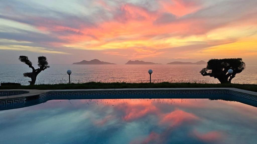 a swimming pool in front of the ocean at sunset at Ocean View Room Oia in Oya