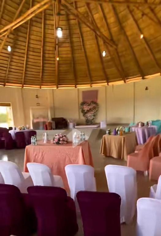a room with tables and white chairs in a room at Omuka owaawe resort in Biguri