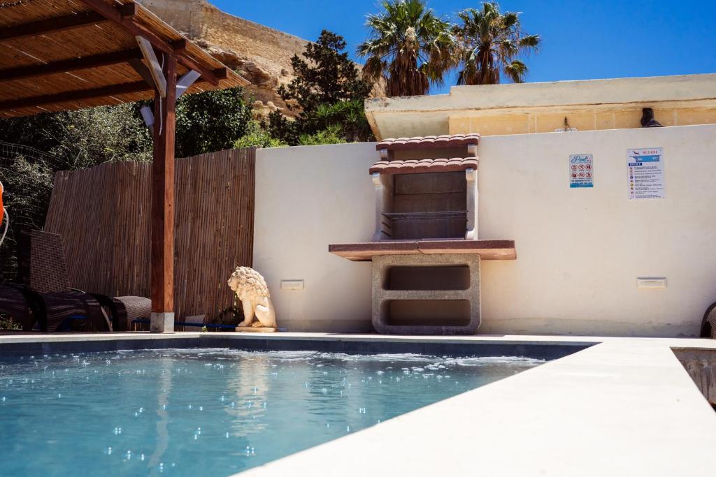 a swimming pool with a chair next to a house at Staytopus Kenn is Sur - Citadel Victoria Gozo Hideaway - Pool in Victoria