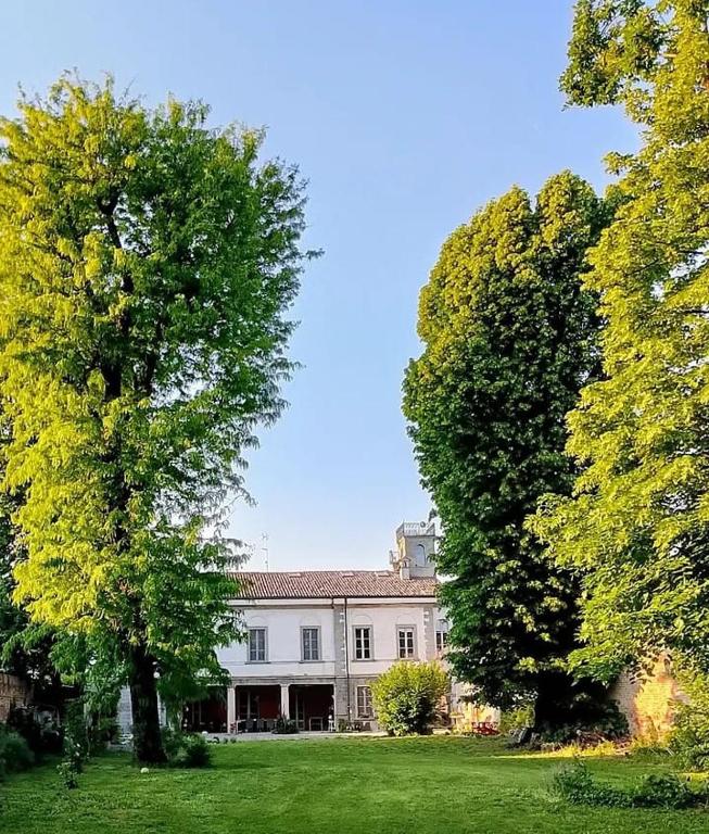 a large white house with trees in front of it at MaVa' Country House in Castelnuovo Bocca dʼAdda